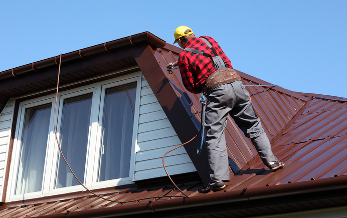 Roofer on a standing seam Metal Roof